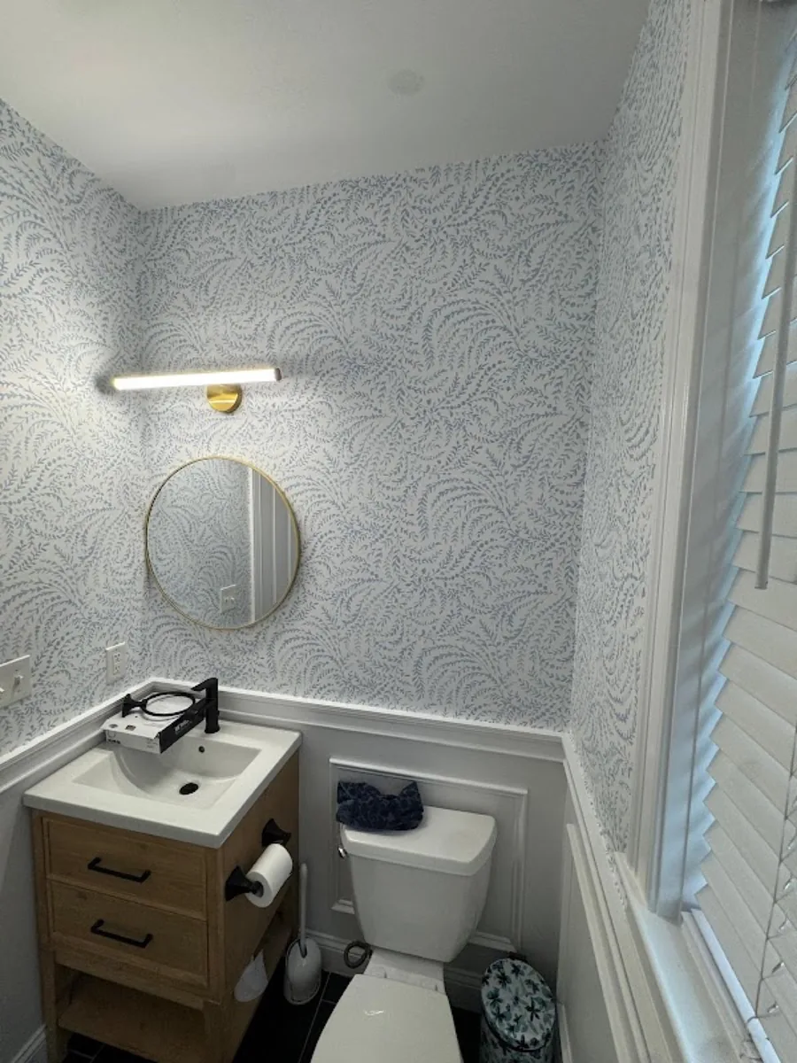 Bathroom remodel with round mirror and wainscoting