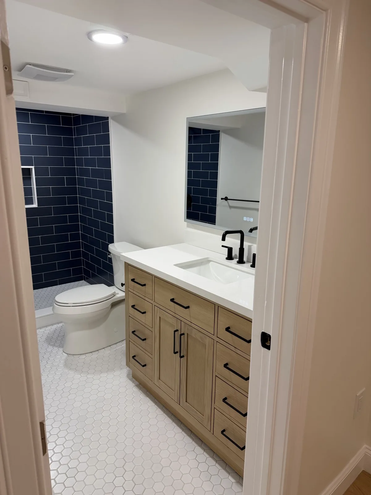 Basement bathroom with navy tile and wood vanity