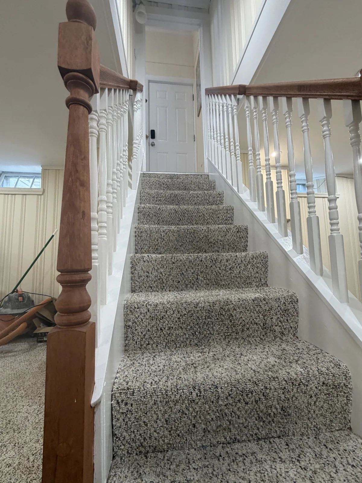 Basement staircase with carpet and wood railing